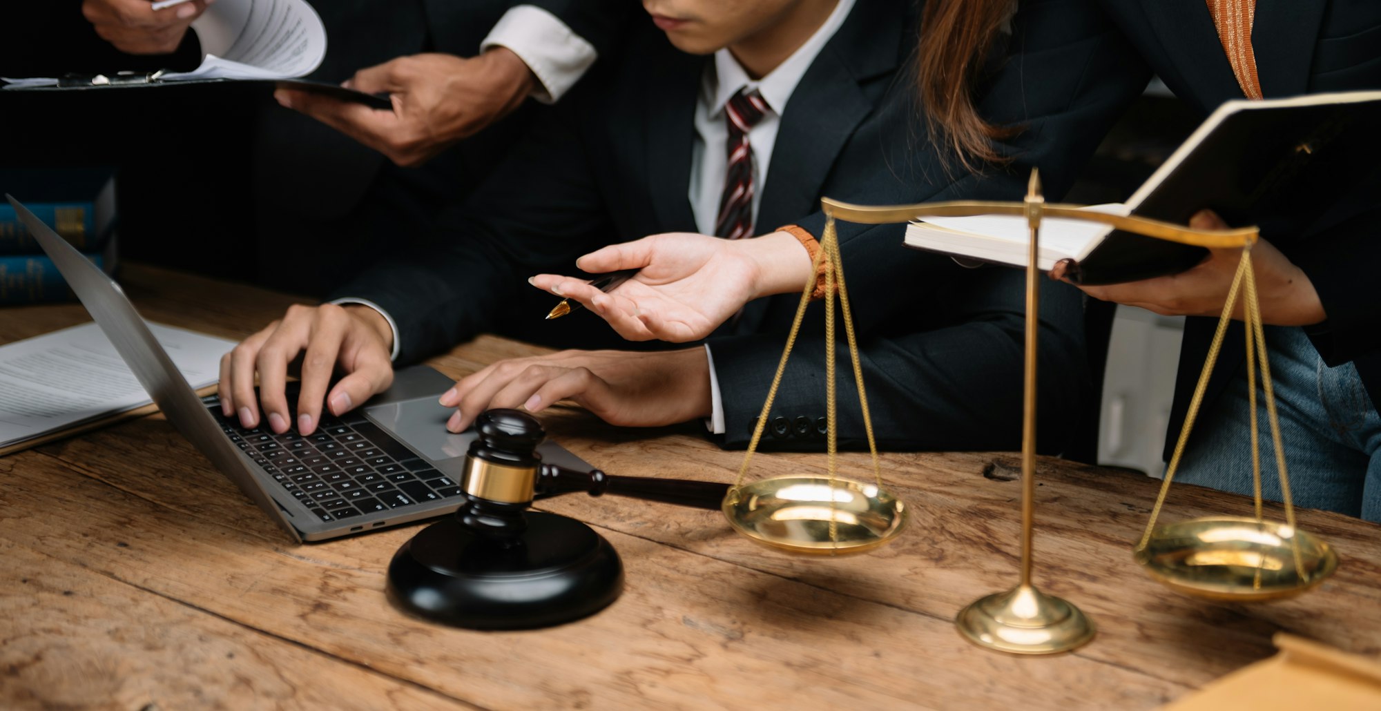 Business and lawyers discussing contract papers with brass scale on desk in office. Law