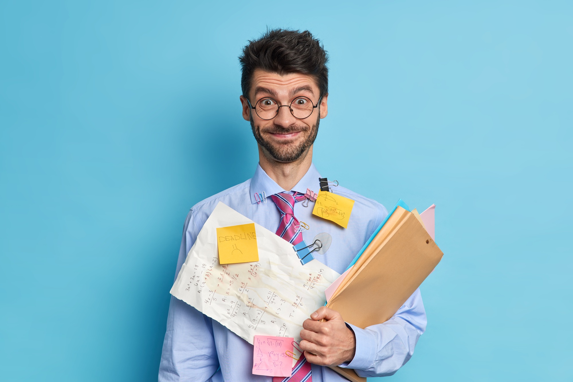 Cheerful bearded male financier prepares stratup project poses with papers and folders dressed in fo